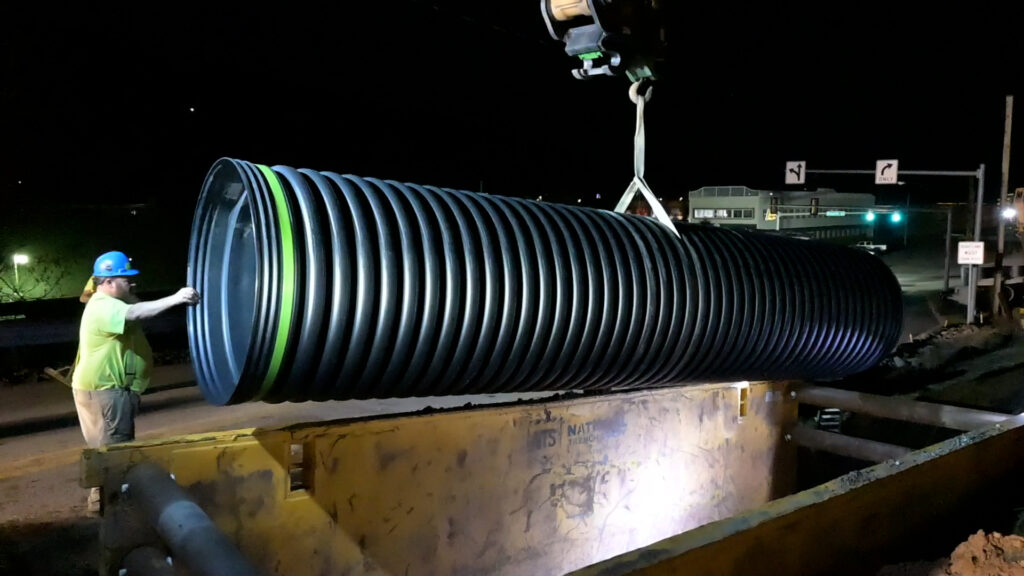A new 48-inch storm pipe is lowered into place during nighttime construction in Honesdale, PA.