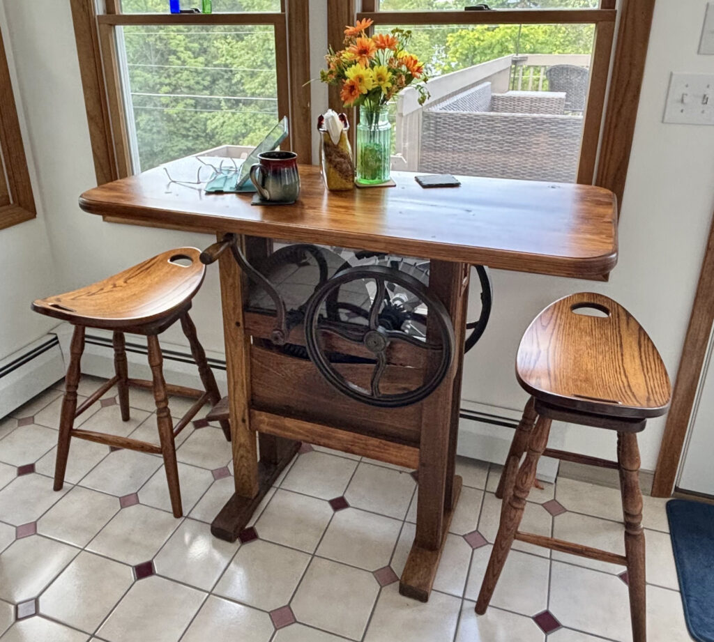 A table Wendy Howells made from an antique corn sheller, with two wooden stools.